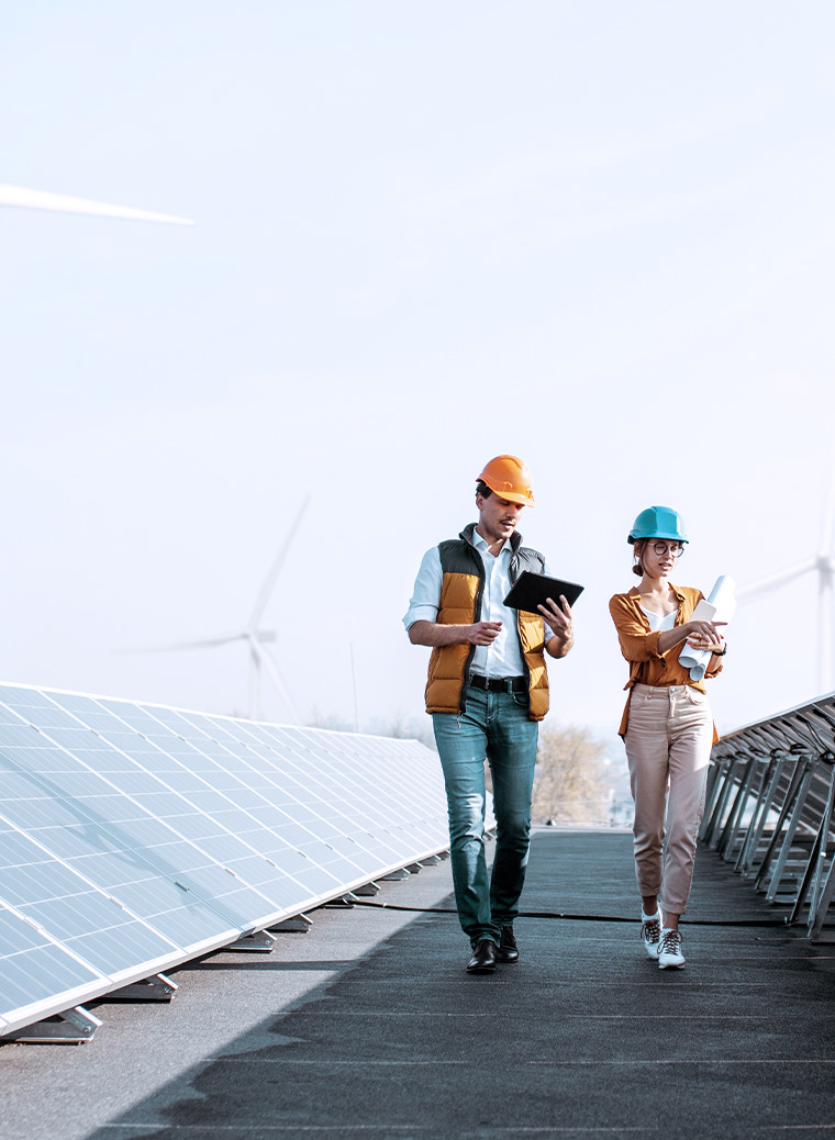 Two People with construction helmets checking their mobile devices in the middle of a solar farm